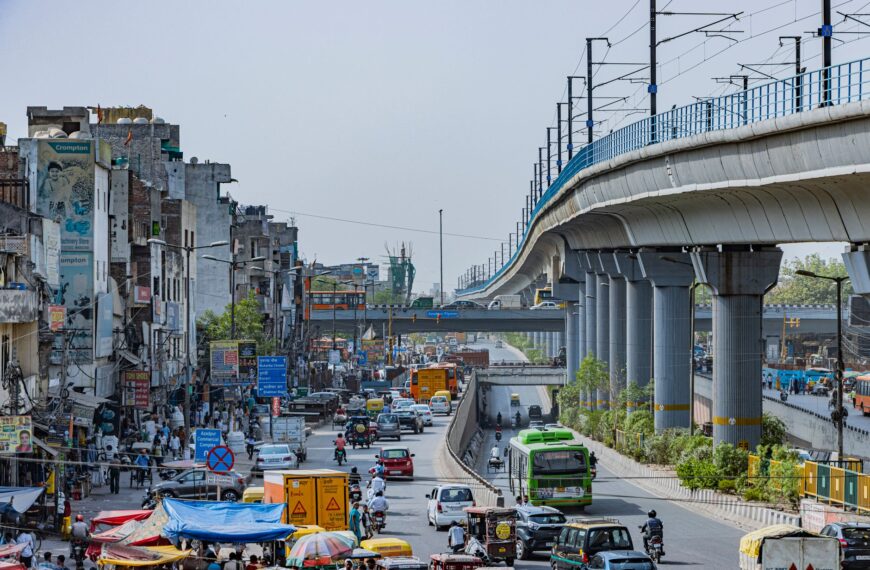 bustling street with elevated metro in delhi