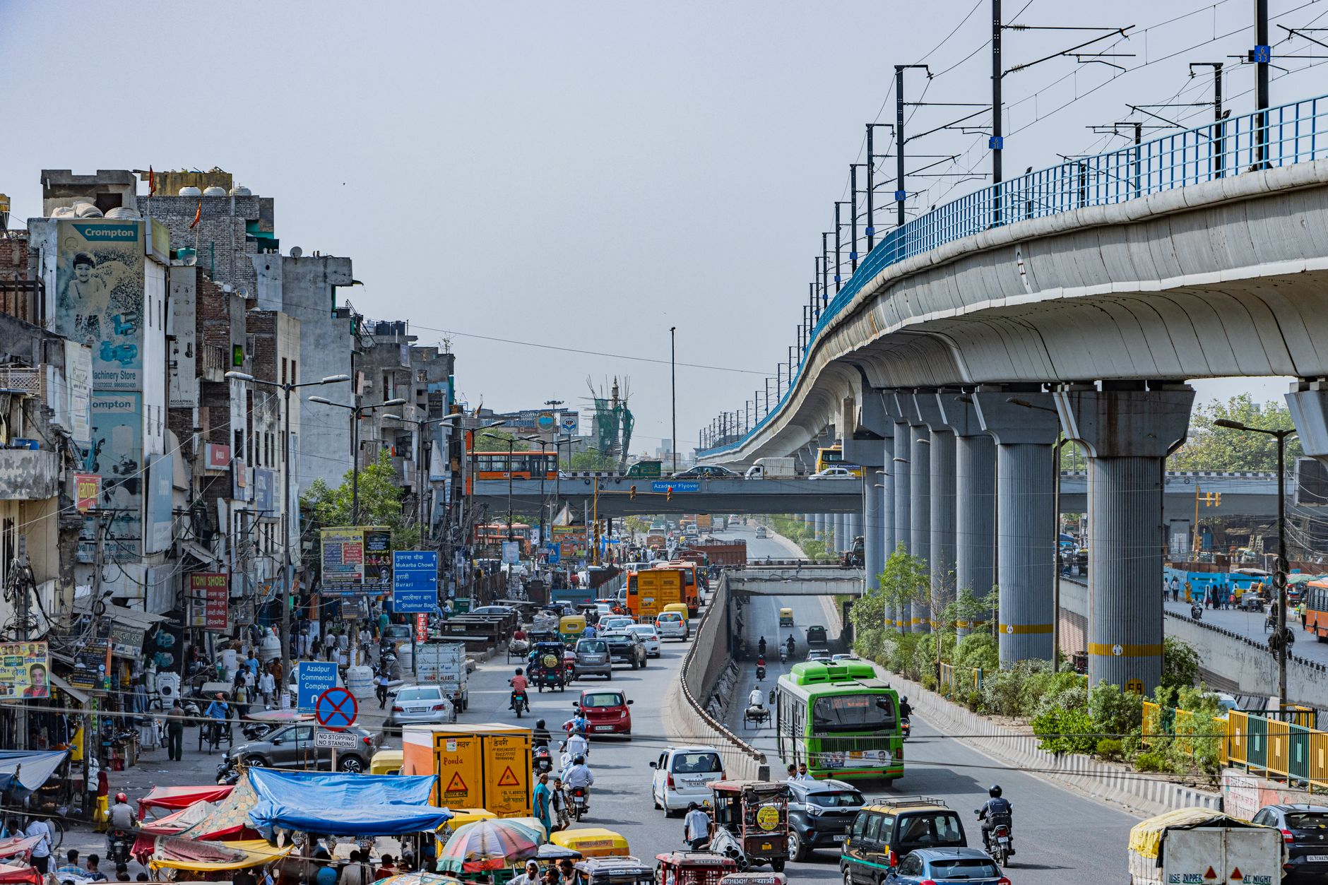 bustling street with elevated metro in delhi